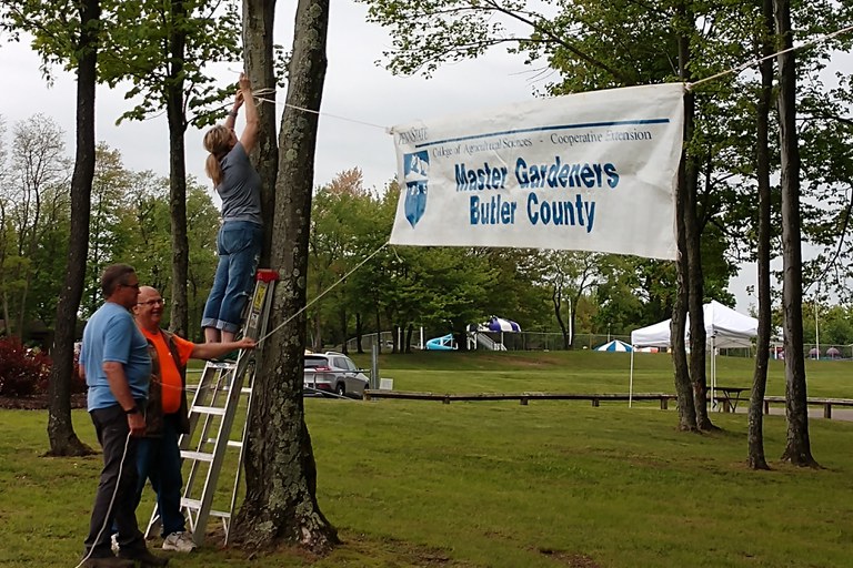 Volunteers hang a banner in preparation of our spring plant sale.