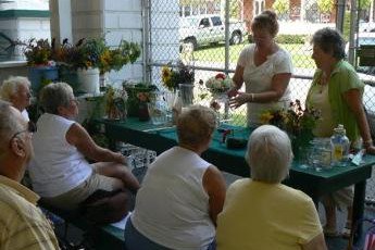 Master Gardeners demonstrate flower arranging to a crowd at the Grange Fair