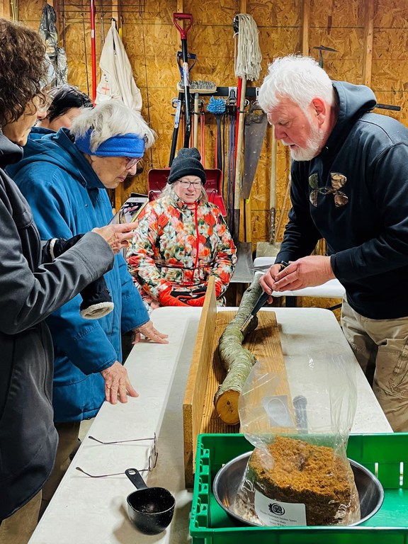 Harry Leslie shows Master Gardeners how to inoculate logs with mushroom spawn. (Photo Credit to Mary Sturdevant)