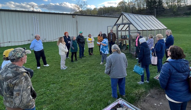 Seed to supper workshop. Participants gathered around a small greenhouse